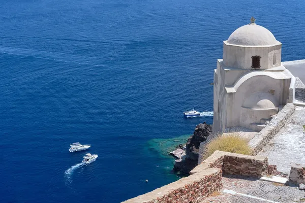 White chapel with a dome above the deep blue sea in Oia, Santorini, Greece