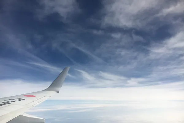 Airplane wing above scattered clouds seen from a passenger window